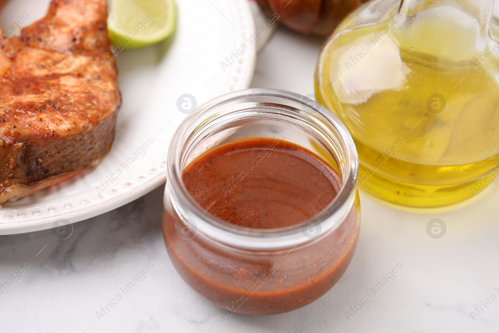 Photo of Fresh marinade, cooked fish and other products on white marble table, closeup