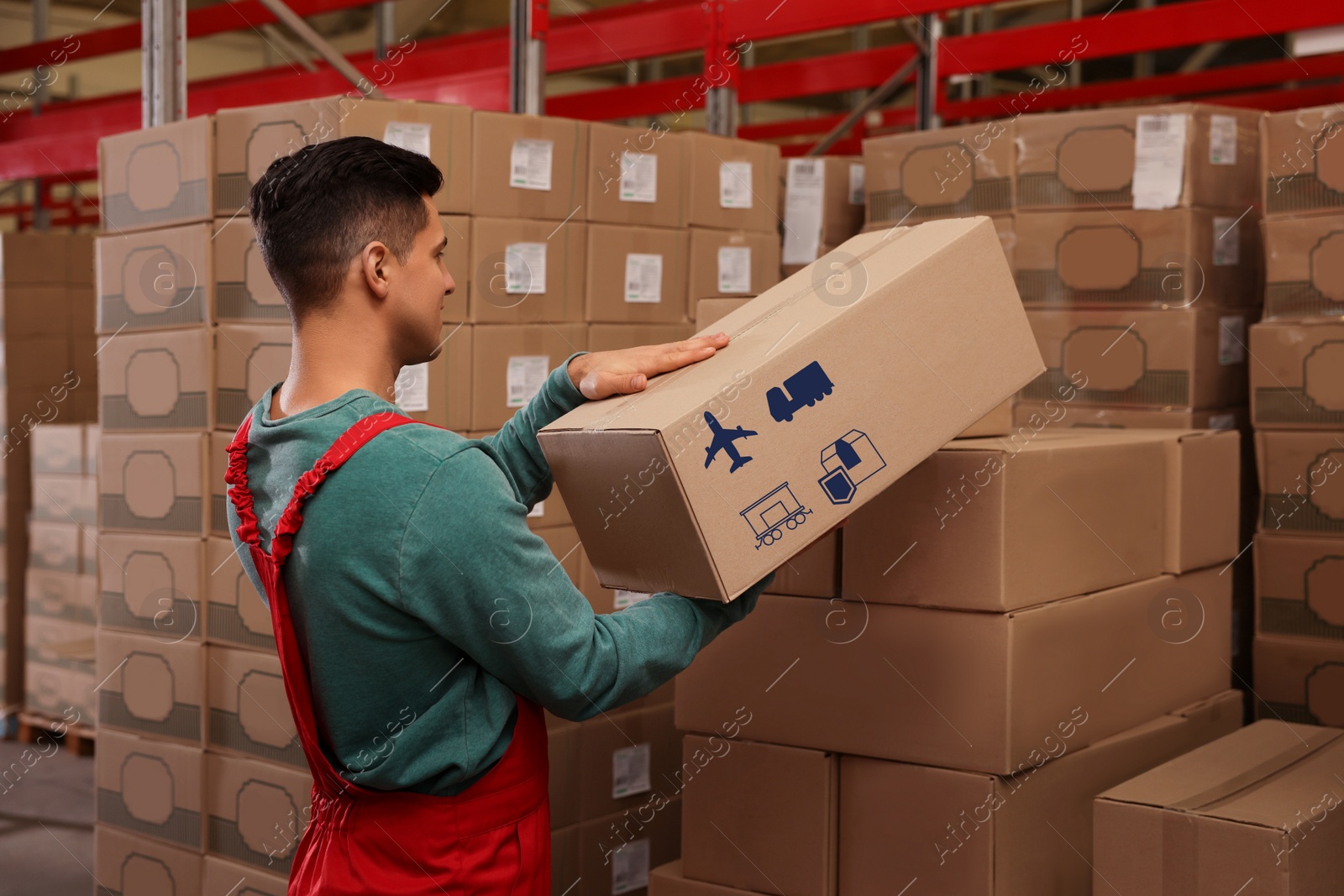 Image of Worker stacking cardboard boxes with shipping icons in warehouse. Wholesaling