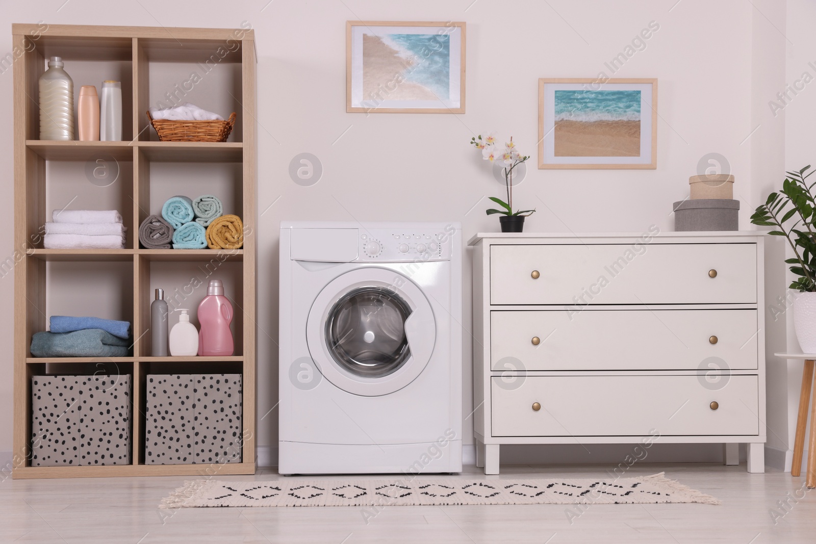 Photo of Stylish laundry room with washing machine and chest of drawers. Interior design