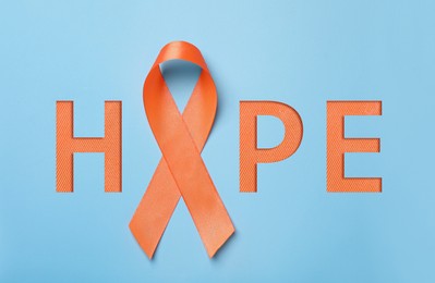 Image of Orange awareness ribbon and word HOPE on light blue background, top view 