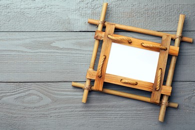 Photo of Empty bamboo frame on grey wooden background, top view. Space for text