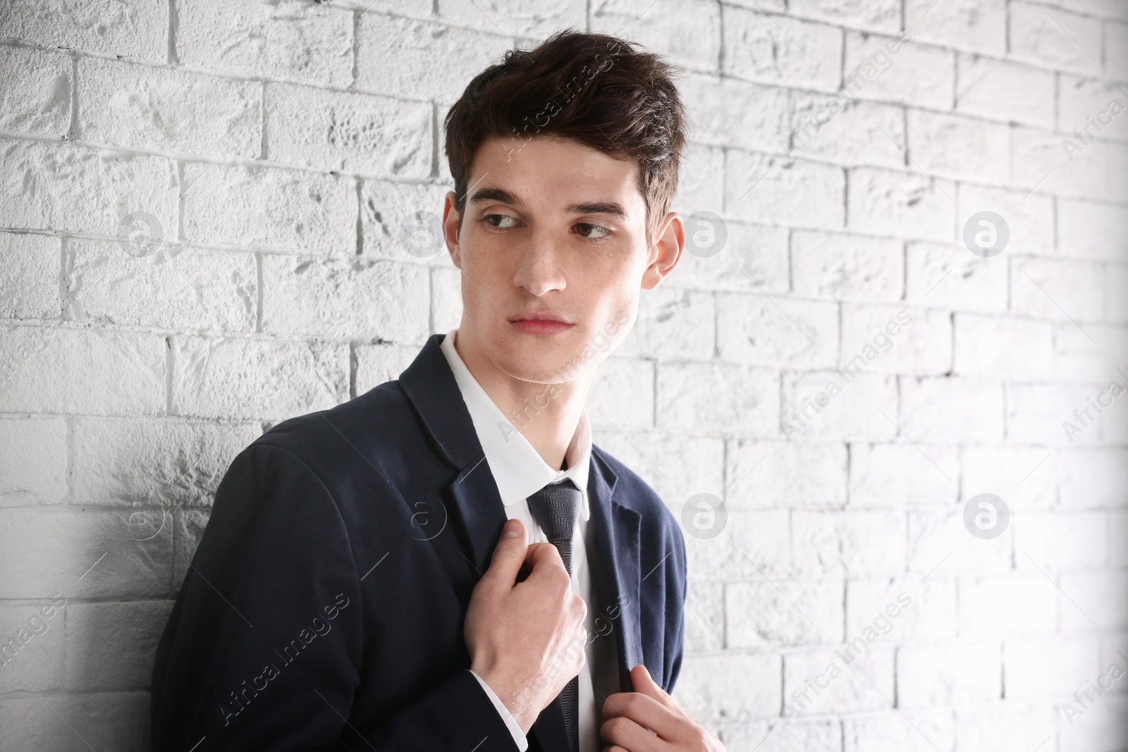 Photo of Portrait of young businessman with beautiful hair on brick wall background