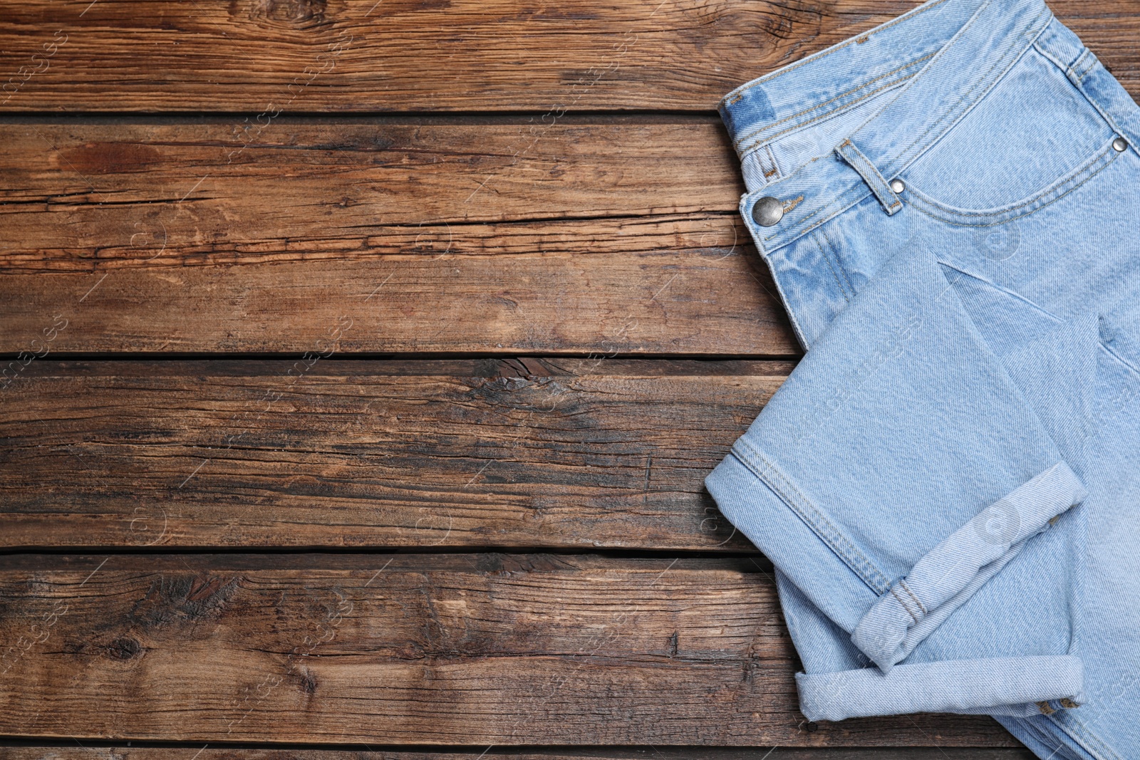 Photo of Stylish jeans on wooden background, top view. Space for text