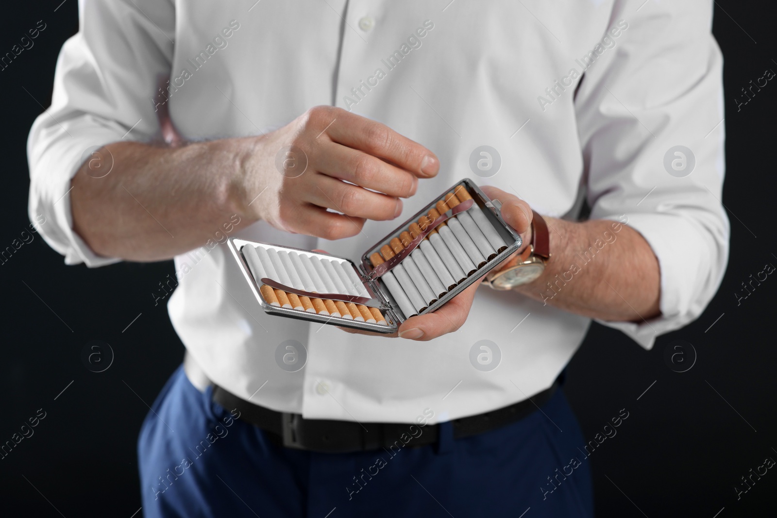 Photo of Man with cigarette holder on black background, closeup