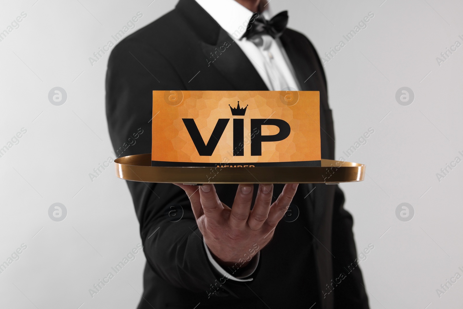 Photo of Man holding tray with VIP sign on light grey background, closeup