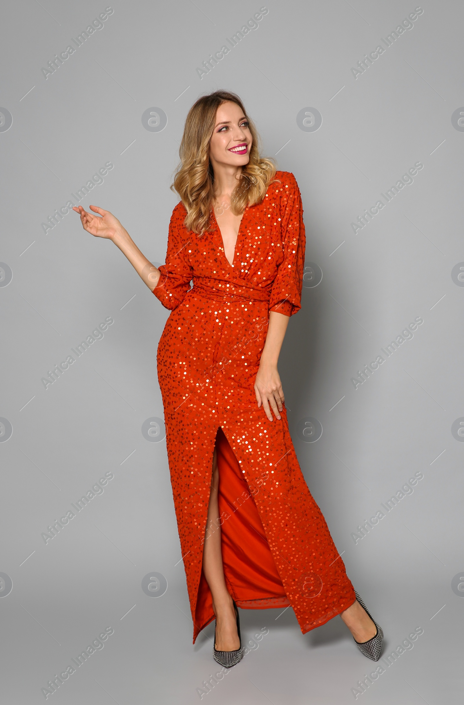 Photo of Happy woman in shiny dress on grey background. Christmas party