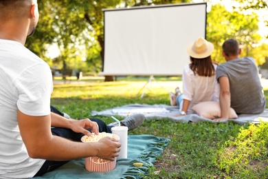 Photo of Young man with popcorn watching movie in open air cinema, closeup. Space for text