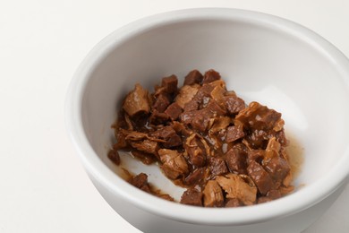 Bowl with wet cat food on white background, closeup
