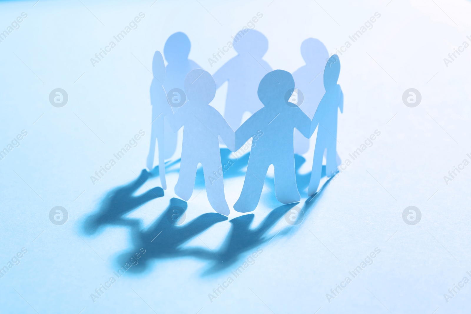Photo of Paper people chain making circle on light blue background. Unity concept