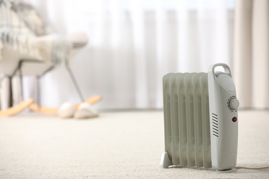 Photo of Modern electric heater on floor at home. Space for text