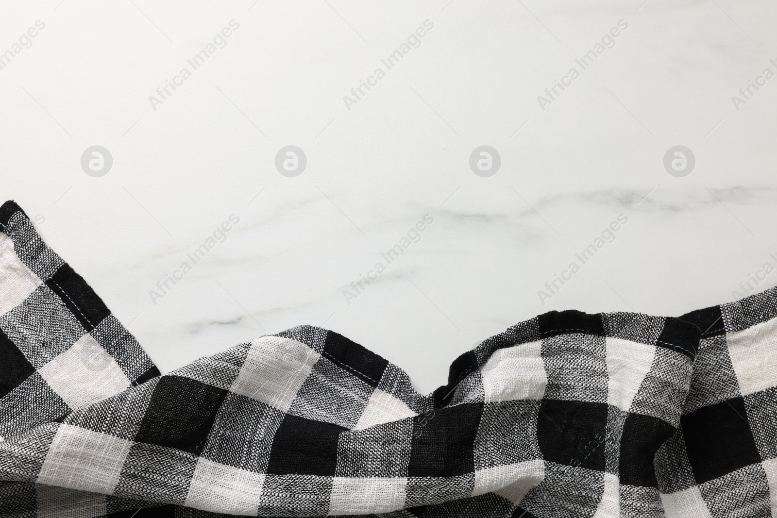 Photo of Black checkered tablecloth on white marble table, top view. Space for text