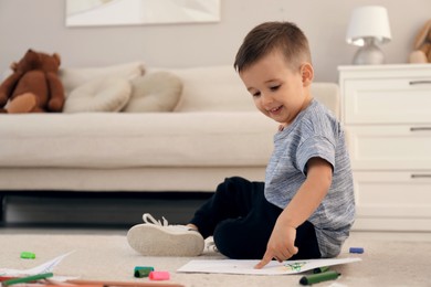 Photo of Cute child drawing on floor at home