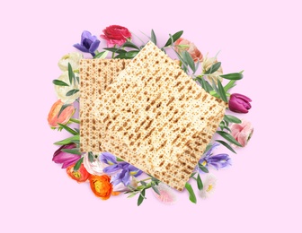 Image of Tasty matzos and flowers on pink background, flat lay. Passover (Pesach) celebration