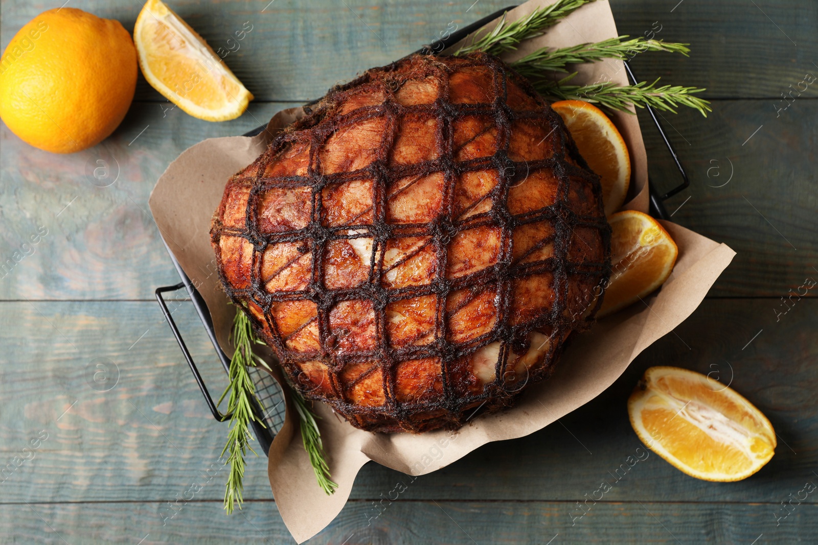 Photo of Delicious baked ham, orange slices and rosemary on rustic wooden table, flat lay