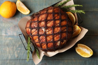Delicious baked ham, orange slices and rosemary on rustic wooden table, flat lay