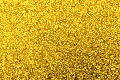 Bright golden glass beads as background, top view