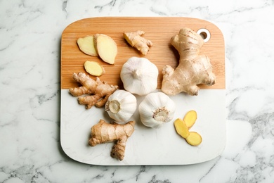Photo of Ginger and fresh garlic on white marble table, top view. Natural cold remedies