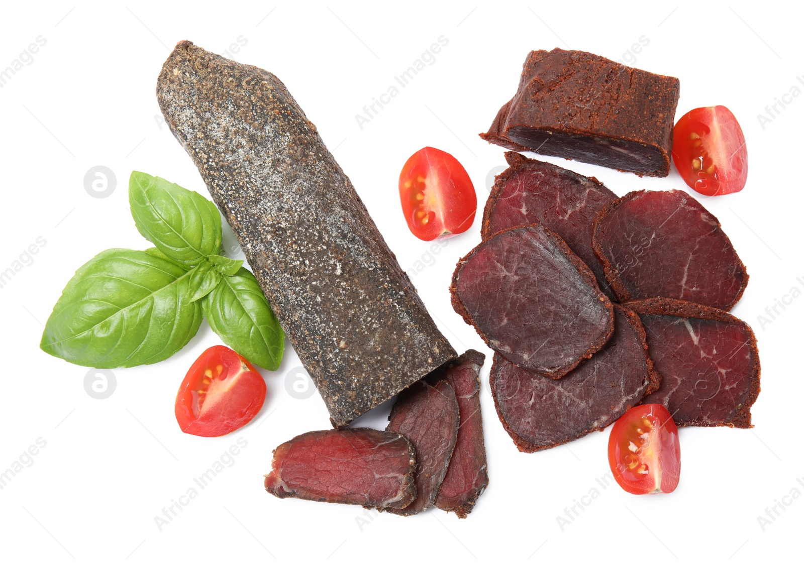 Photo of Delicious dry-cured beef basturma with basil and tomatoes on white background, top view