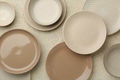 Beautiful ceramic plates and bowls on beige table, flat lay