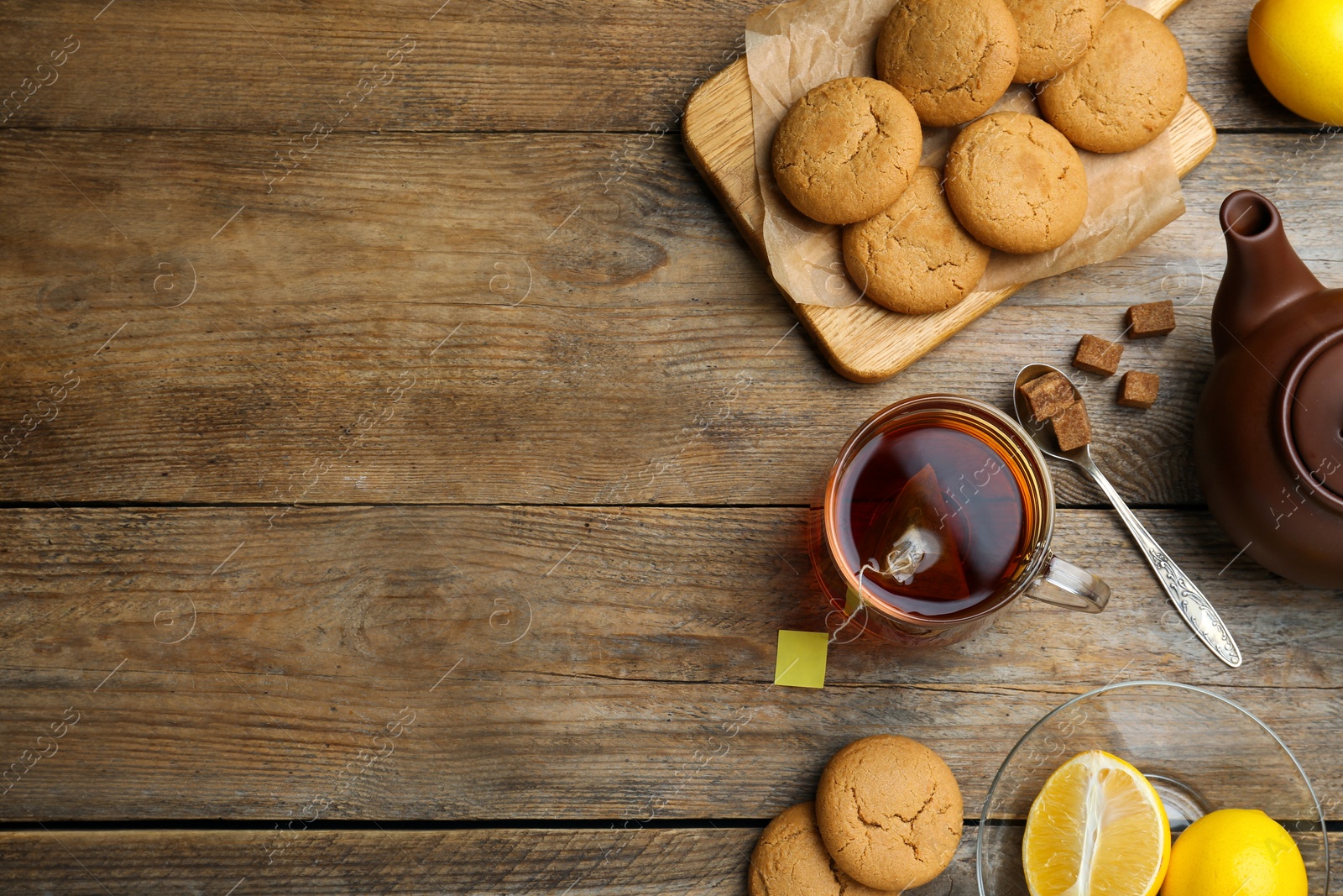 Photo of Flat lay composition with tea bag in glass cup of hot water on wooden table, space for text