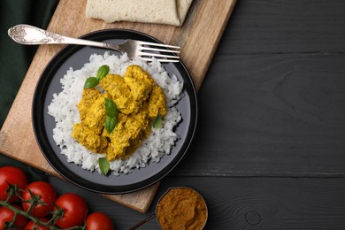 Photo of Delicious rice with chicken curry and products on grey wooden table, flat lay. Space for text