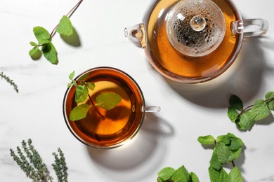 Aromatic herbal tea with mint and thyme on white table, flat lay