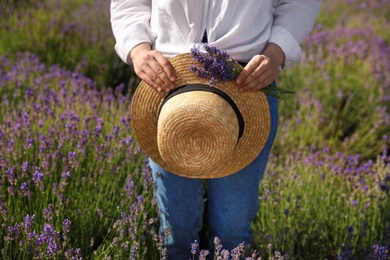 Photo of Young woman with straw hat and lavender bouquet in field on summer day, closeup