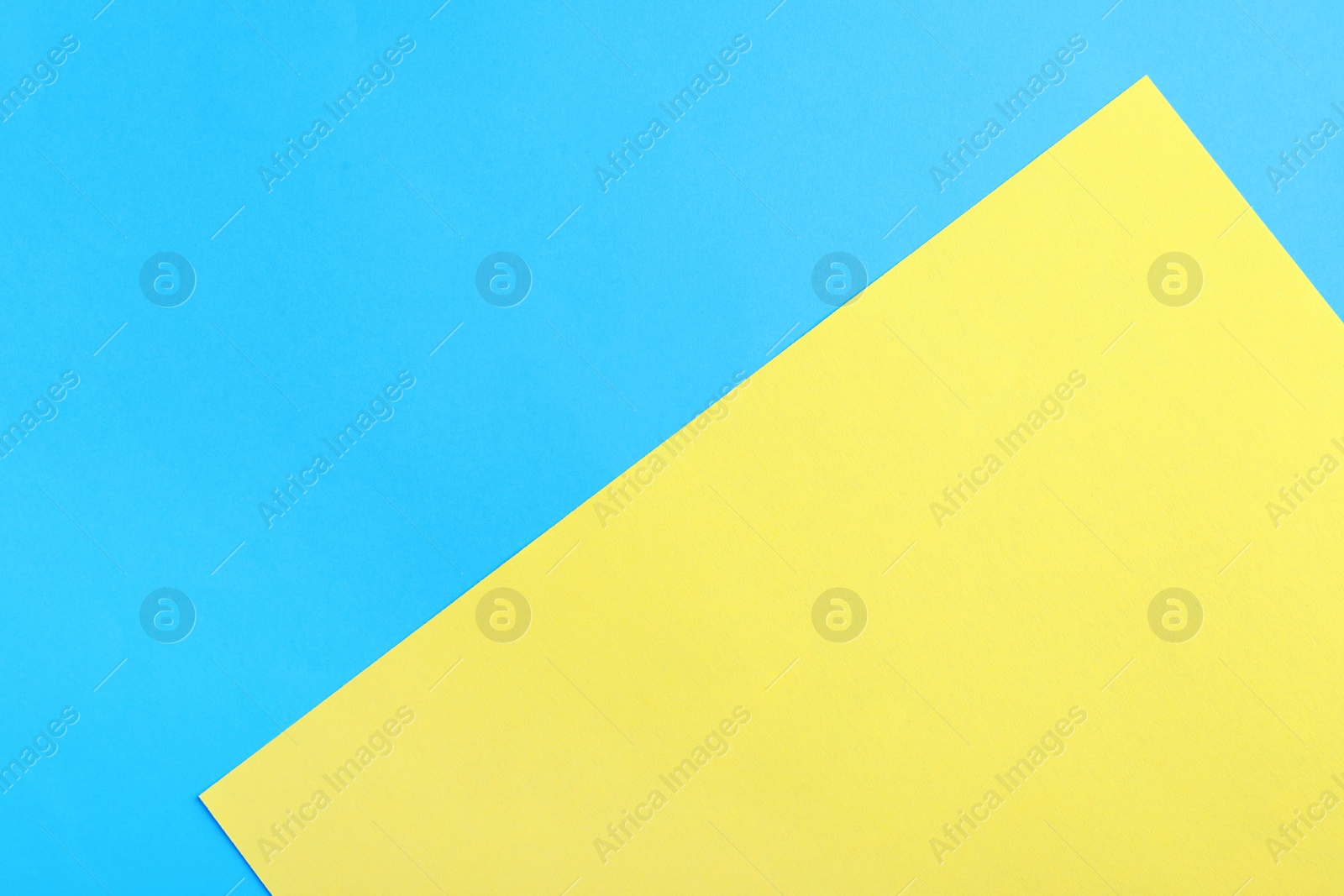 Photo of Blue and yellow paper sheets as colorful background, top view