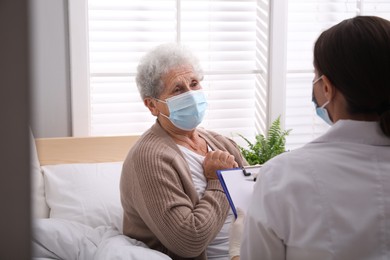 Doctor examining senior woman with protective mask at nursing home