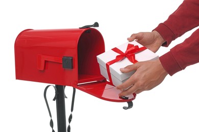 Photo of Man putting Christmas gift into mailbox on white background, closeup. Sending present by mail