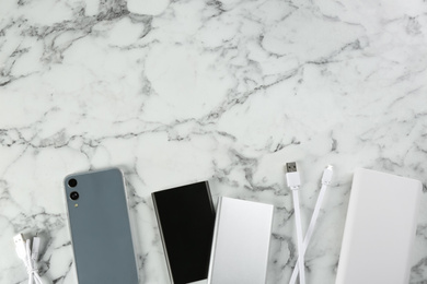 Photo of Flat lay composition with mobile phone and portable chargers on white marble background. Space for text
