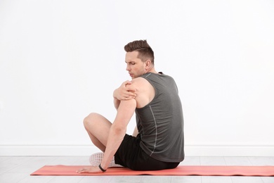 Photo of Male athlete suffering from shoulder pain during training indoors