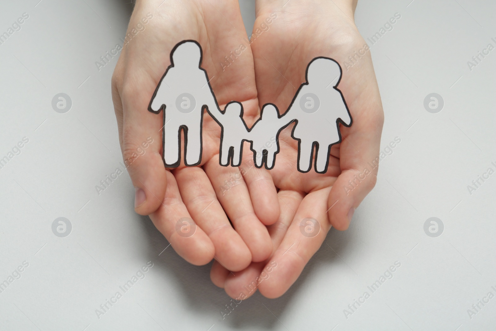 Photo of Woman holding paper family cutout on light grey background, closeup