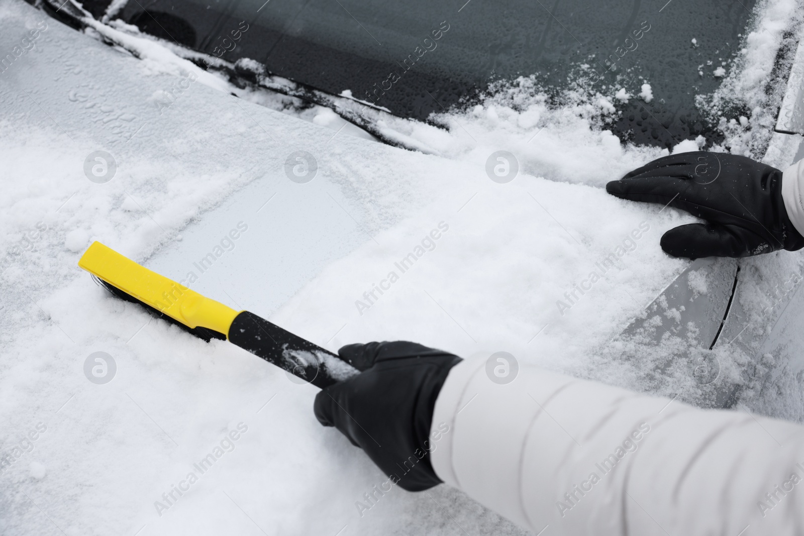 Photo of Man cleaning snow from car hood outdoors, closeup