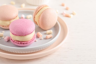 Photo of Delicious colorful macarons and marshmallows on white wooden table, closeup. Space for text