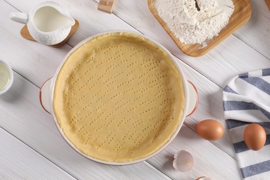 Photo of Pie tin with fresh dough and ingredients on white wooden table, flat lay. Making quiche