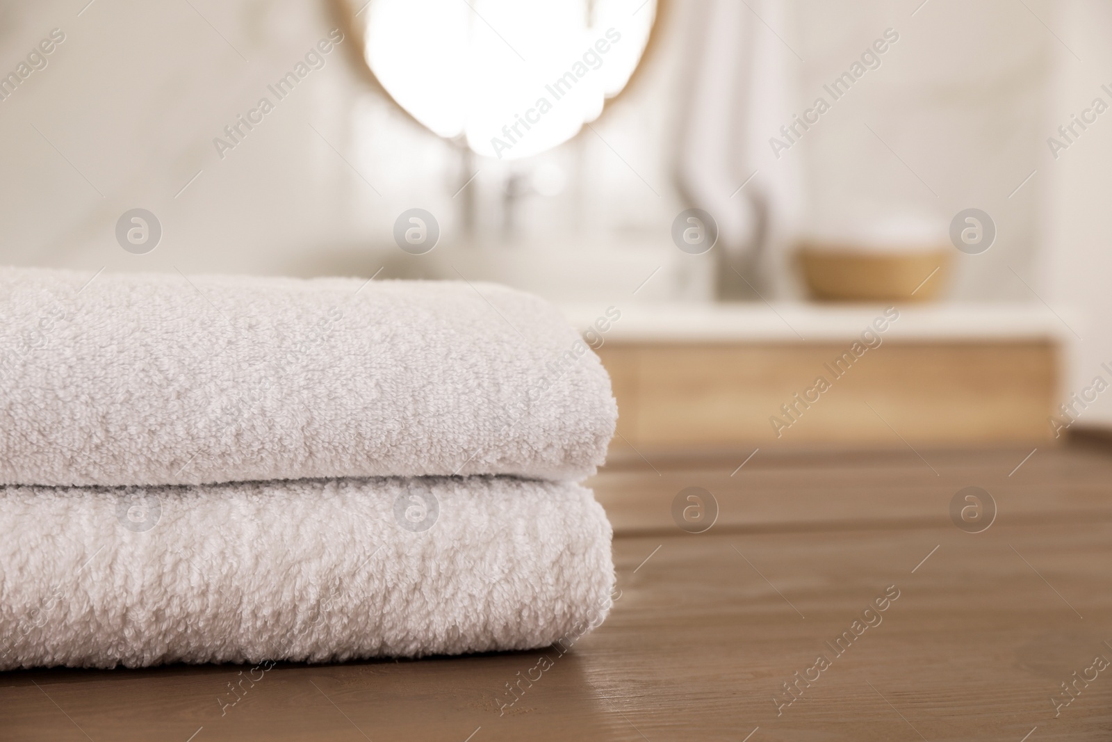 Photo of Stack of clean towels on wooden table in bathroom. Space for text