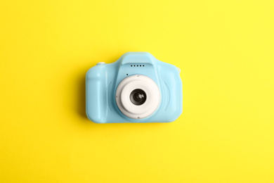 Photo of Light blue toy camera on yellow background, top view. Future photographer