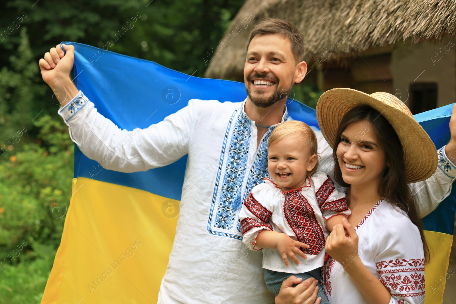 Photo of Happy family in national clothes with flag of Ukraine outdoors