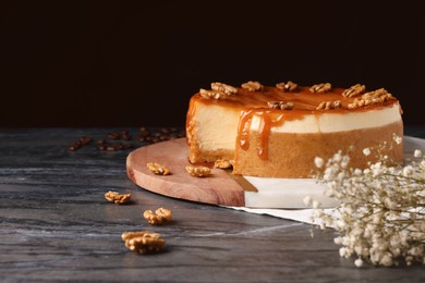Delicious cheesecake with caramel and walnuts on black marble table, space for text