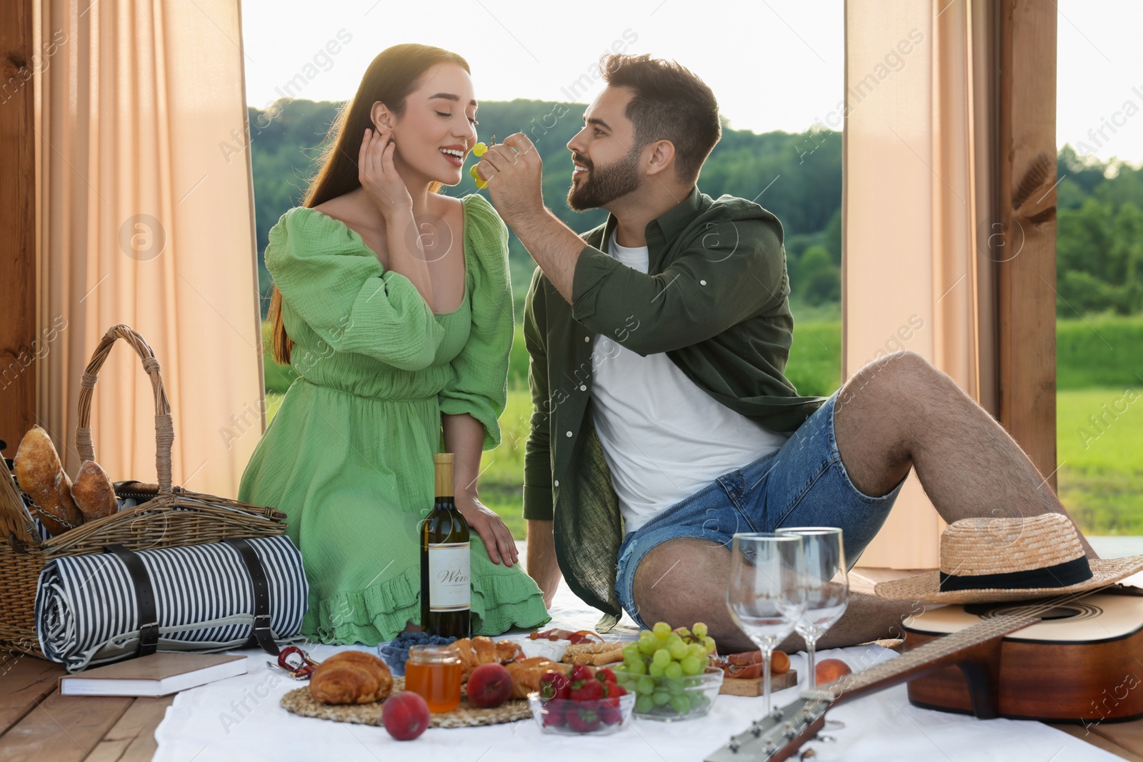 Photo of Romantic date. Beautiful couple having picnic in wooden gazebo