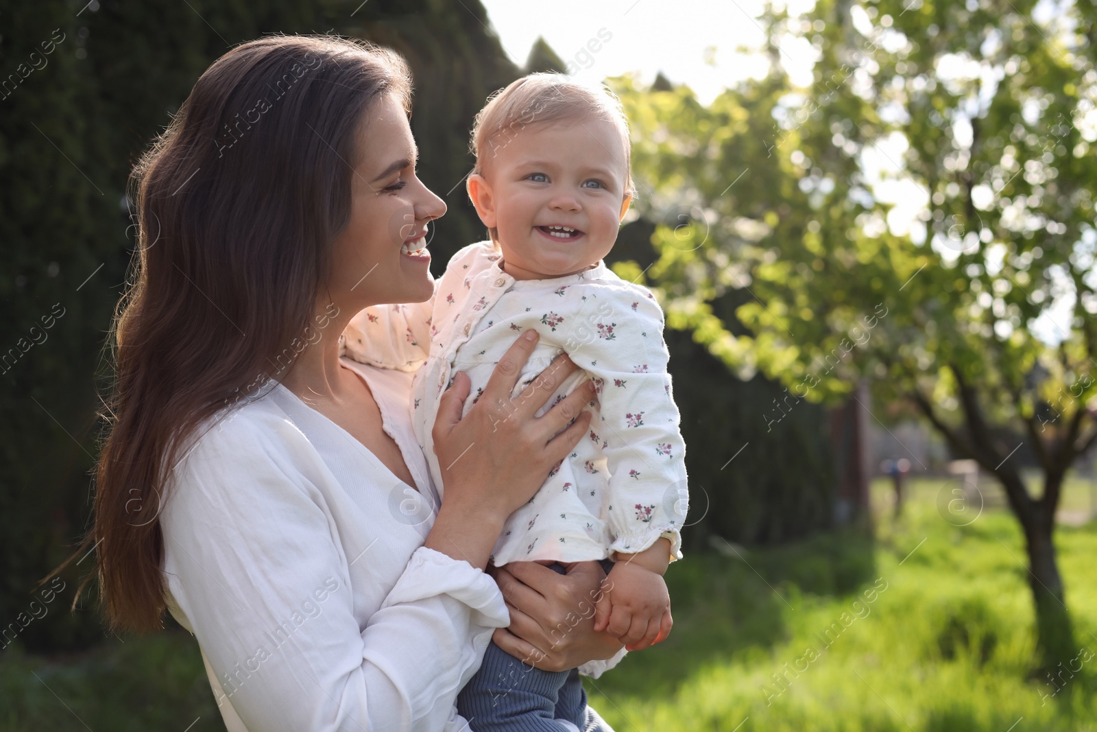 Photo of Happy mother with her cute baby in park on sunny day, space for text