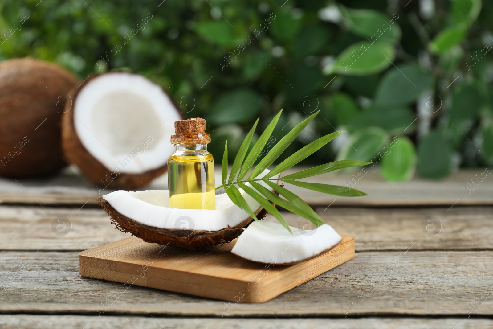 Photo of Bottle of organic coconut cooking oil, fruit pieces and leaf on wooden table. Space for text