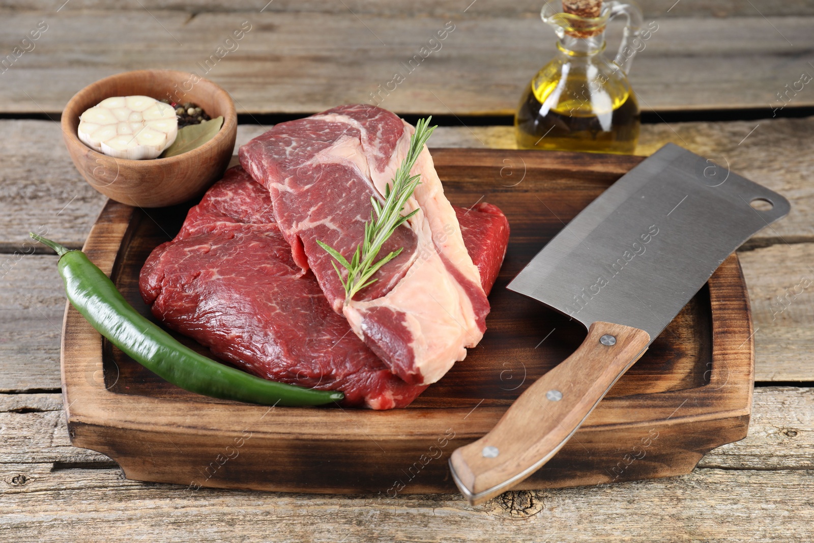 Photo of Fresh raw beef cut, spices and butcher knife on wooden table