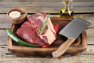 Photo of Fresh raw beef cut, spices and butcher knife on wooden table