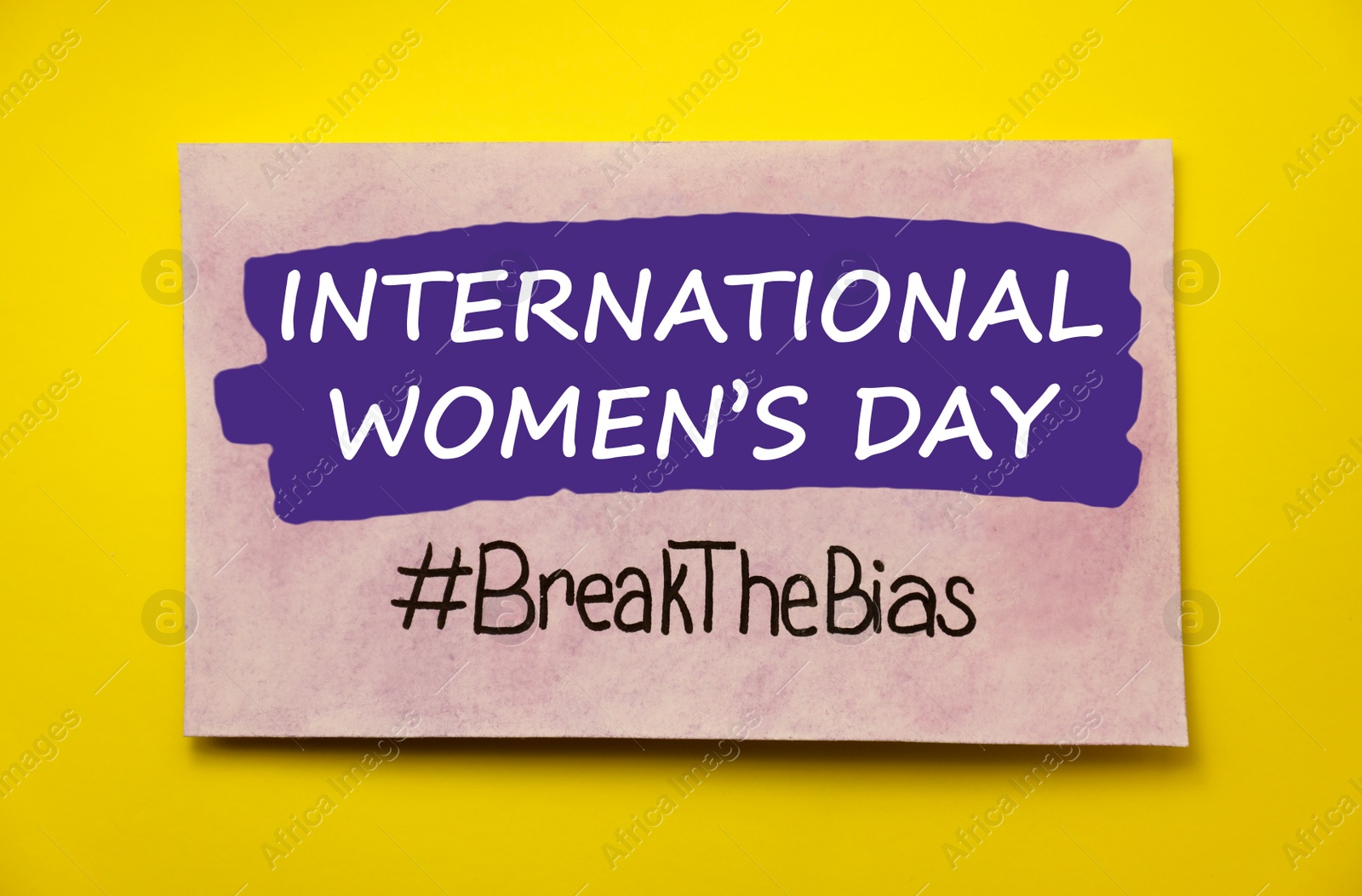 Photo of Card with text International Women's Day and hashtag BreakTheBias on yellow background, top view