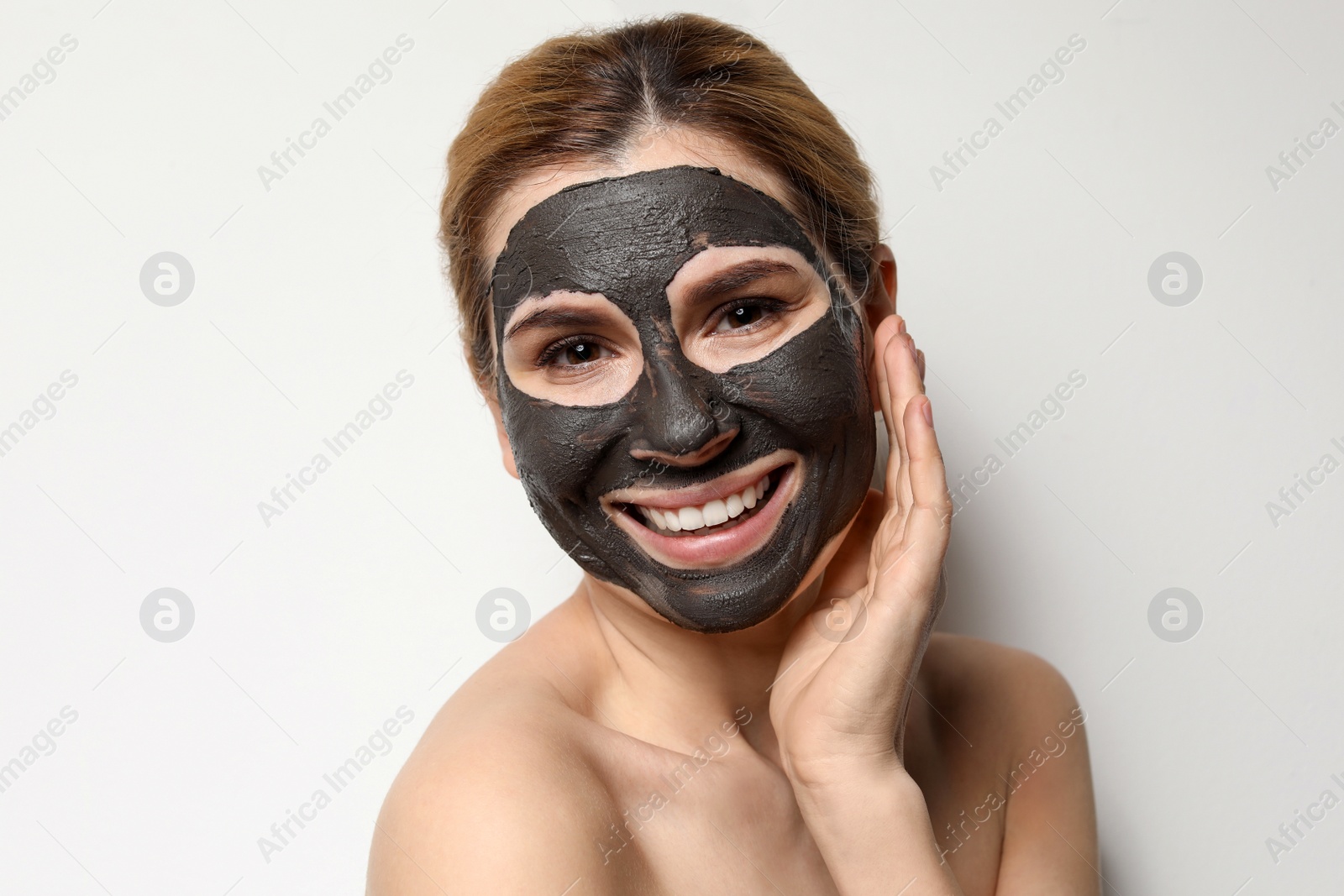 Photo of Beautiful woman with black mask on face against light background