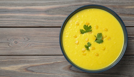 Delicious creamy corn soup served on wooden table, top view. Space for text