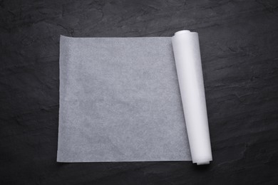 Photo of Roll of baking paper on black table, top view