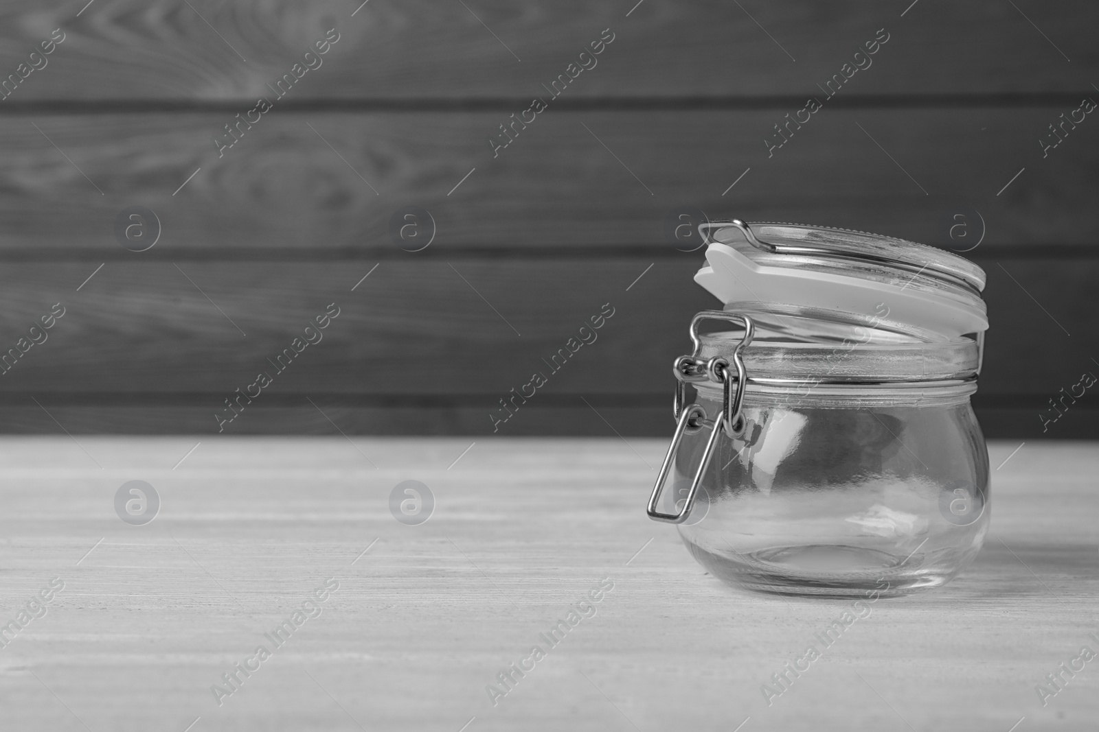 Photo of Empty glass jar on white wooden table, space for text